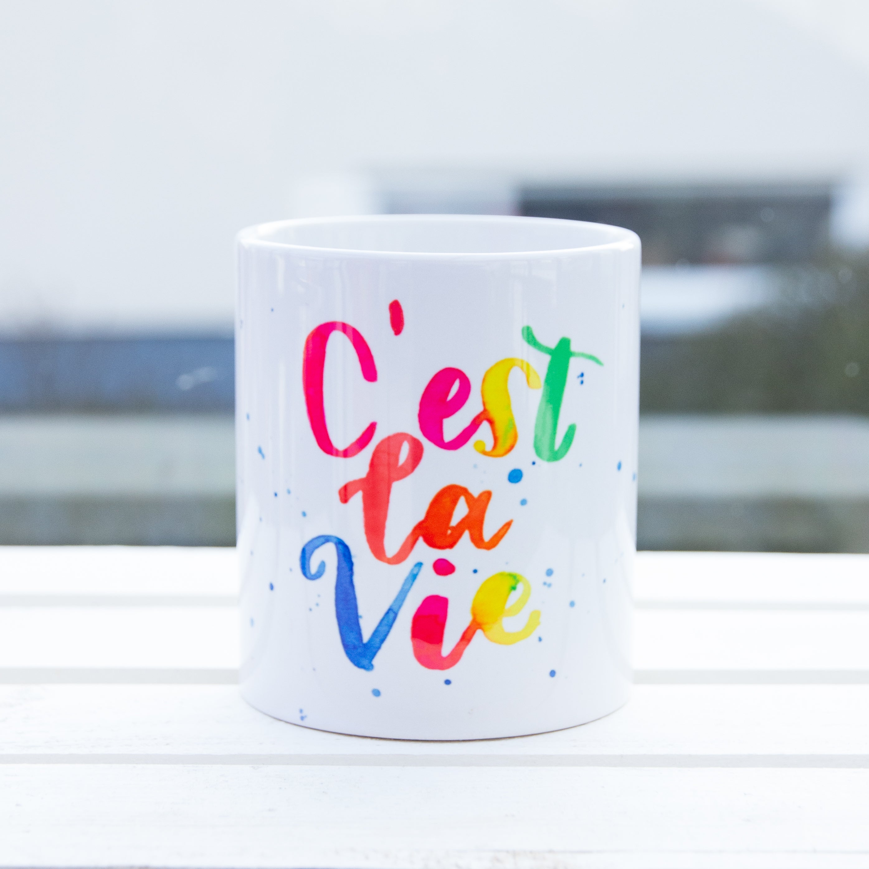 weiße Tasse mit buntem Handlettering Aufdruck C'est la vie Frontansicht
